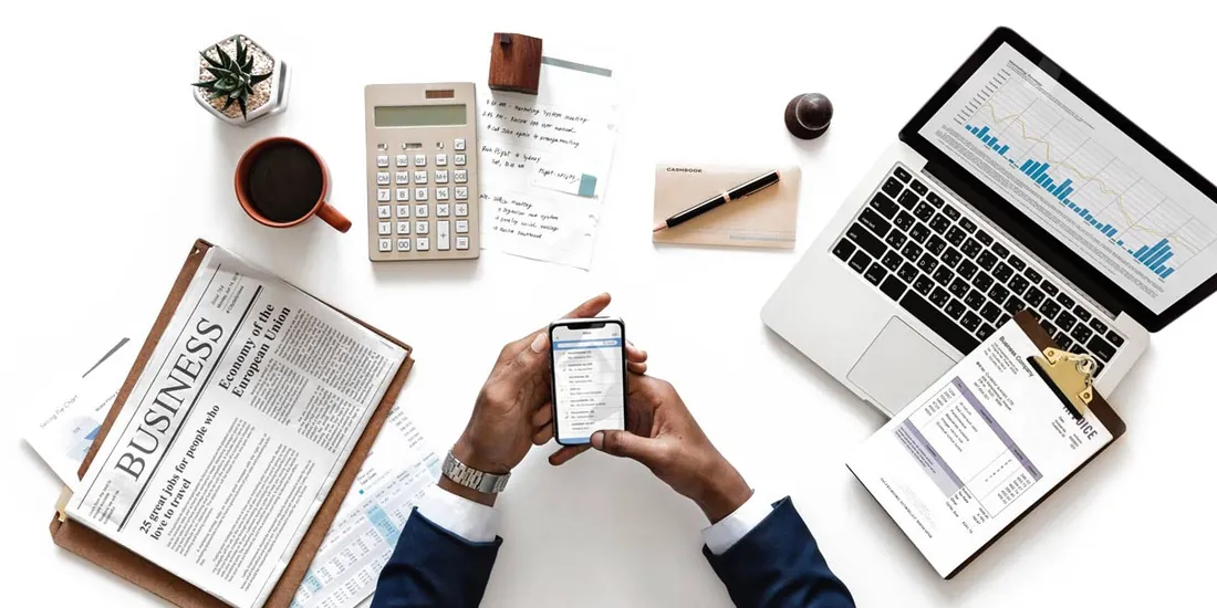 Desk with a laptop showing revenue analytics and a hand using a phone