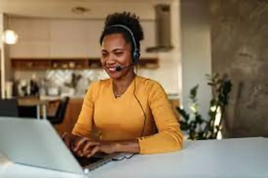Smiling customer service agent wearing a headset working at a laptop
